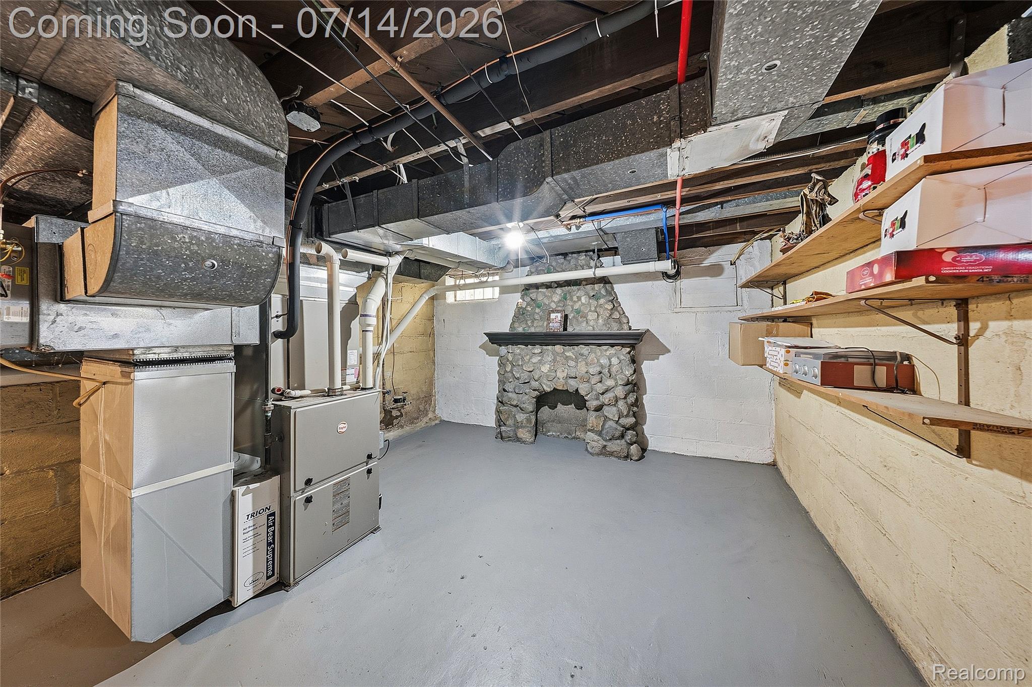 18460 Meridian Road Grosse Ile, MI 48138 - Photo 41 of 50 Basement featuring a stone fireplace, built-in shelving, painted concrete flooring, and exposed ceiling joists with utility ductwork