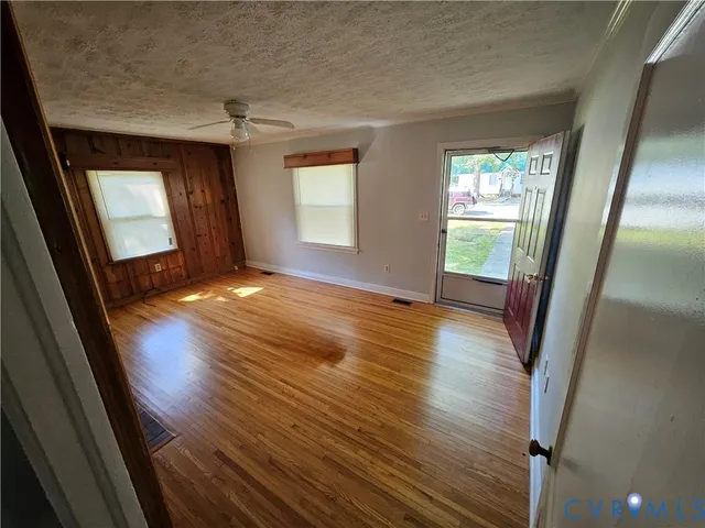 an empty room with wooden floor and windows