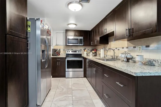 a kitchen with stainless steel appliances granite countertop a refrigerator a sink a stove a microwave and wooden cabinets