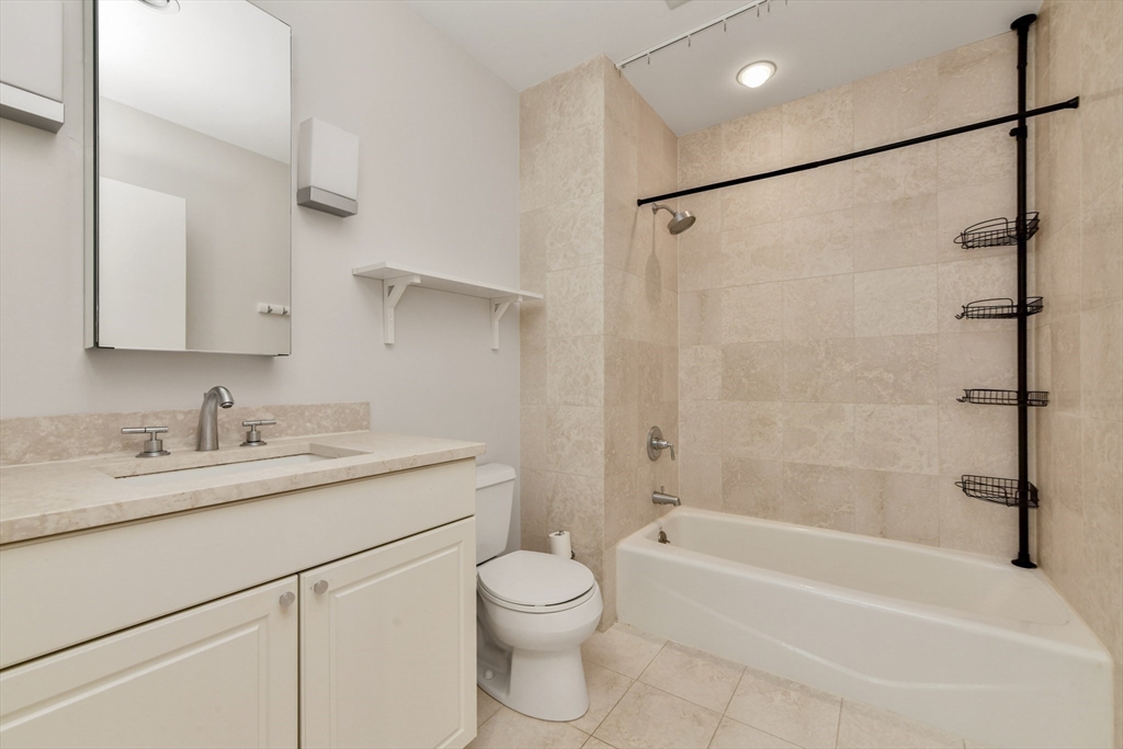 80 Broad Street, Unit 603 Boston, MA 02110 - Photo 13 of 16 a bathroom with a granite countertop sink toilet and shower