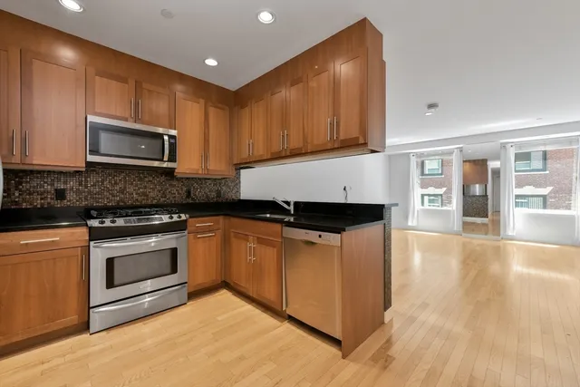 a kitchen with stainless steel appliances granite countertop wooden cabinets a stove top oven a sink and dishwasher