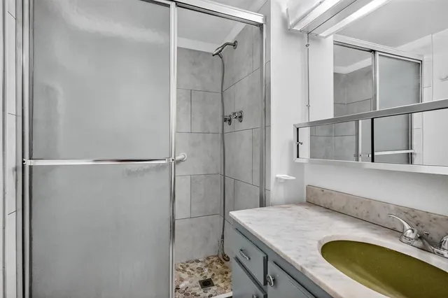 a bathroom with a granite countertop sink a mirror and shower