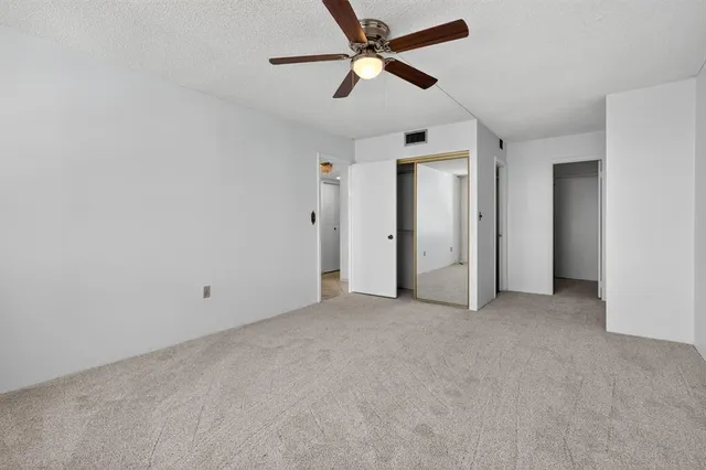 an empty room with closet and a ceiling fan