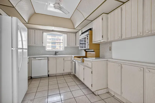a kitchen with white cabinets and white appliances