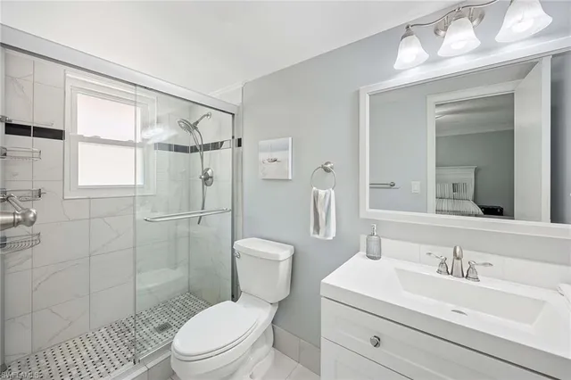 a bathroom with a toilet a sink a glass door a shower a mirror and vanity