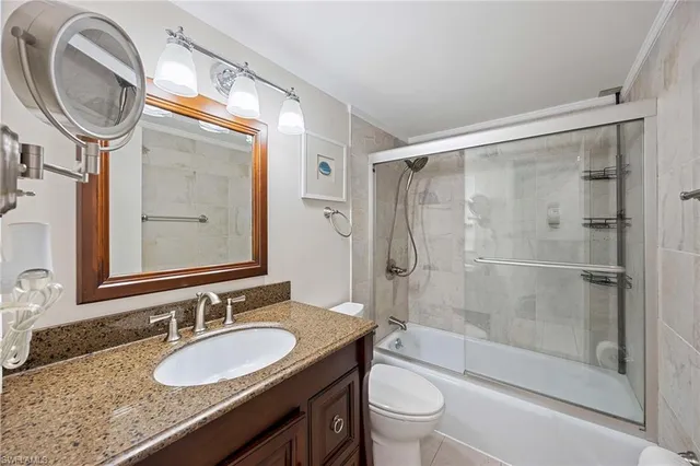 a bathroom with a granite countertop sink toilet and a mirror