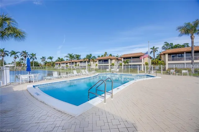 a view of a swimming pool with a lawn chairs under an umbrella