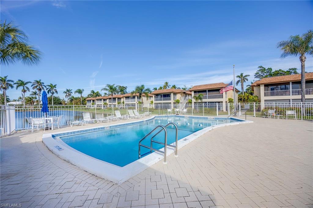 1155 Sandpiper Street, Unit G6 Naples, FL 34102 - Photo 24 of 30 a view of a swimming pool with a lawn chairs under an umbrella
