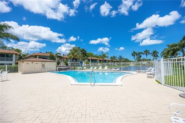 a view of a swimming pool with a lawn chairs under an umbrella