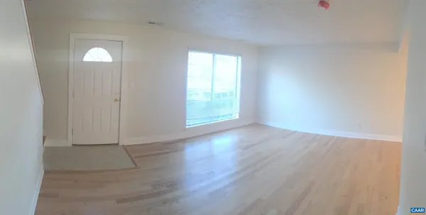 an empty room with wooden floor and windows