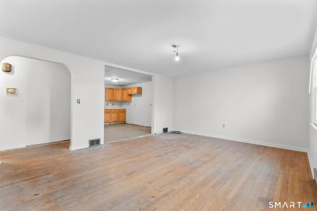a view of an empty room with wooden floor and cabinets
