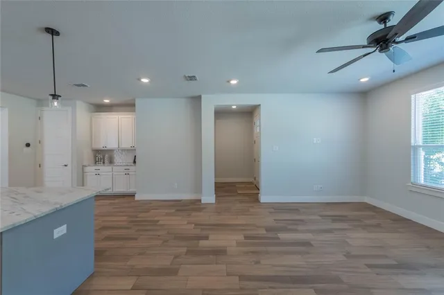 a view of an empty room with a kitchen and a window