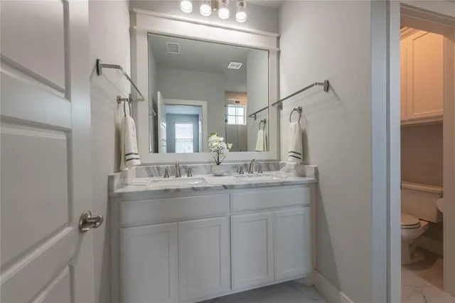 a bathroom with a granite countertop sink a toilet and a mirror