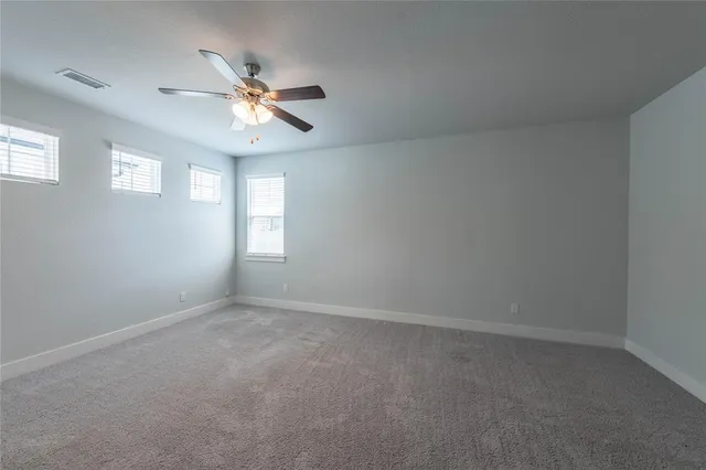an empty room with windows and fan