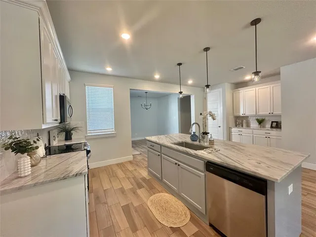 a kitchen with stainless steel appliances granite countertop a sink a stove and a wooden floors