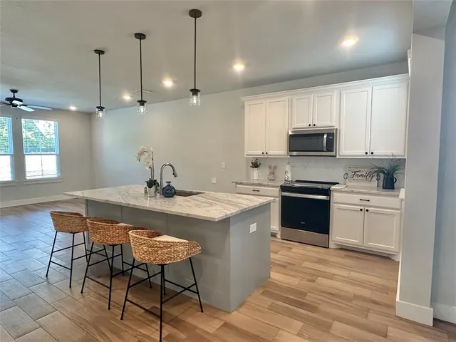 a kitchen with a stove a sink a microwave a counter space and cabinets