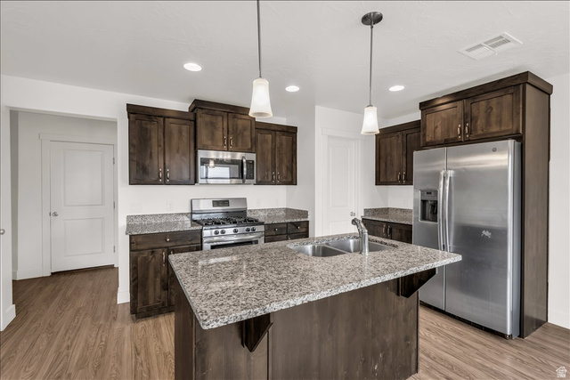 5875 Challenger Way St. George, UT 84790 - Photo 4 of 18 Kitchen featuring an island with a dual-basin sink, pendant lighting, stainless steel appliances, granite countertops, and wood-finish flooring