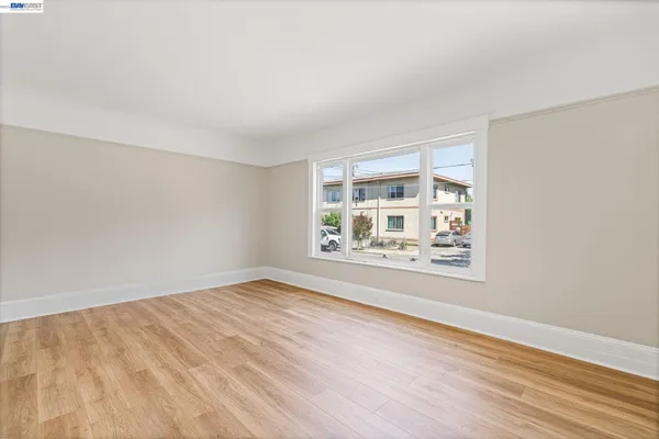 a view of empty room with wooden floor and window
