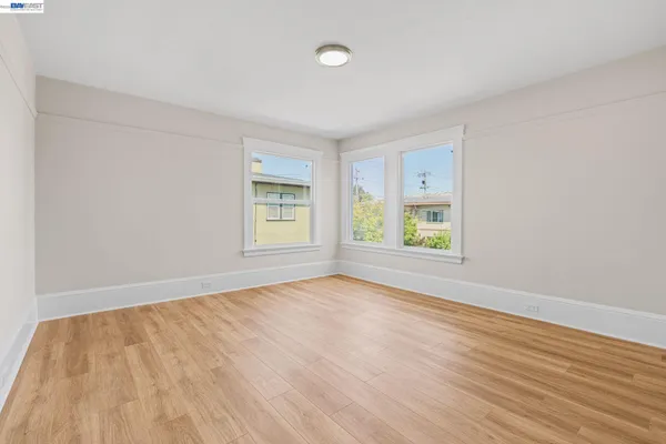 a view of an empty room with window and wooden floor