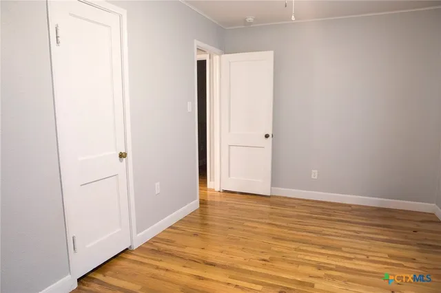 a view of an empty room with wooden floor