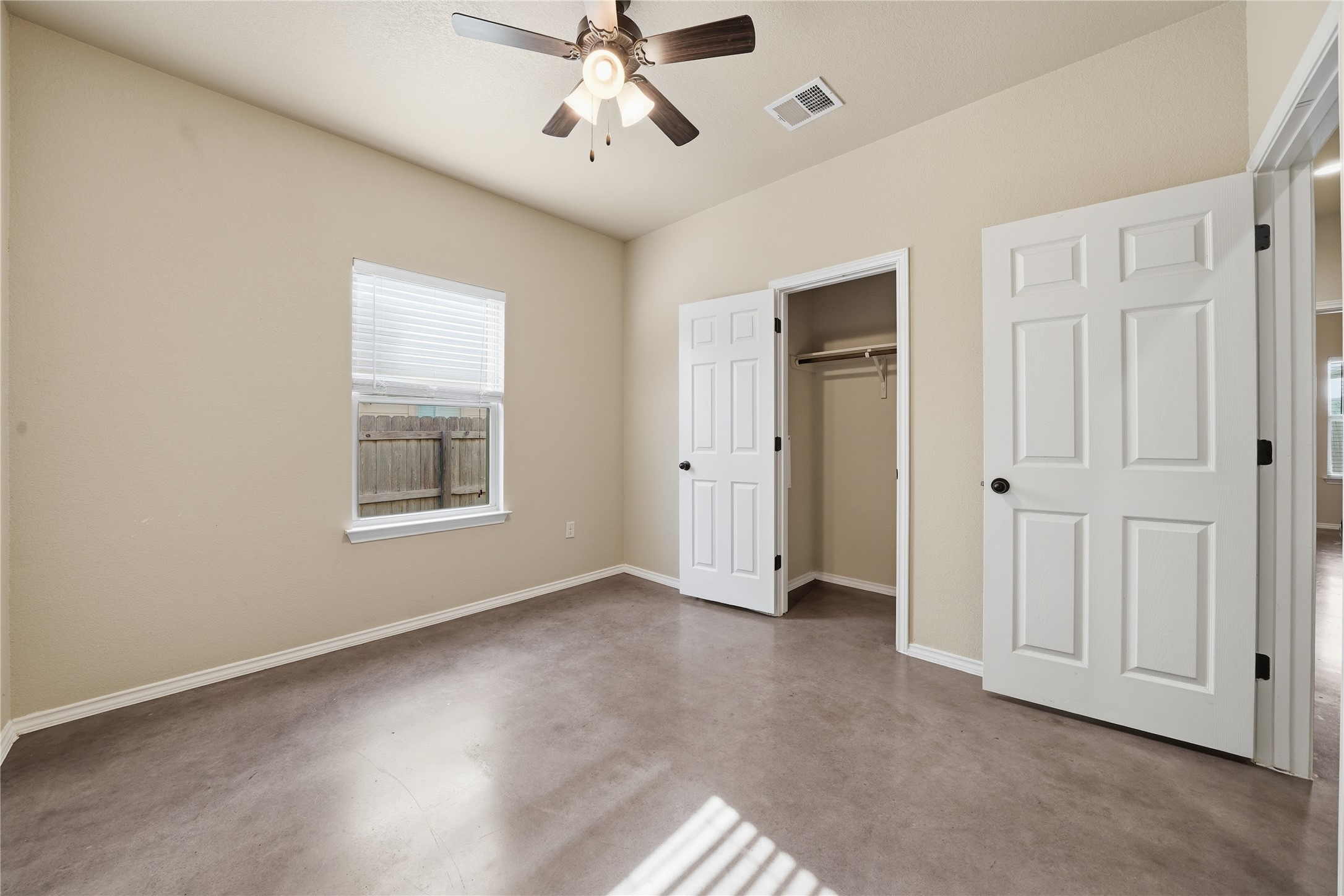 533 Jack Rabbit Lane, Unit A Buda, TX 78610 - Photo 19 of 34 A well-lit bedroom features durable concrete flooring and a ceiling fan for comfort.