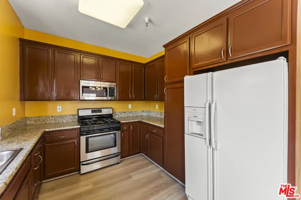 a kitchen with stainless steel appliances granite countertop a refrigerator and a stove top oven