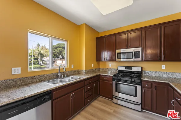 a kitchen with stainless steel appliances granite countertop a stove a sink and a microwave