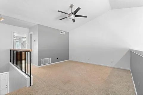 an empty room with wooden floor and a ceiling fan