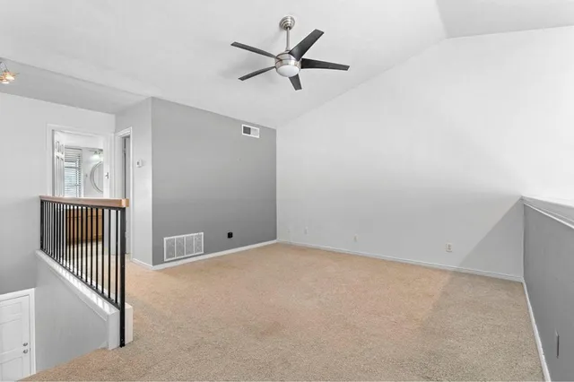 an empty room with wooden floor and a ceiling fan