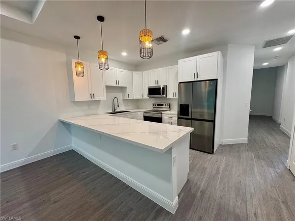 a kitchen with kitchen island white cabinets and stainless steel appliances