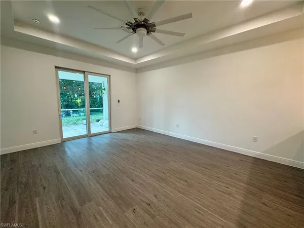 an empty room with wooden floor fan and windows
