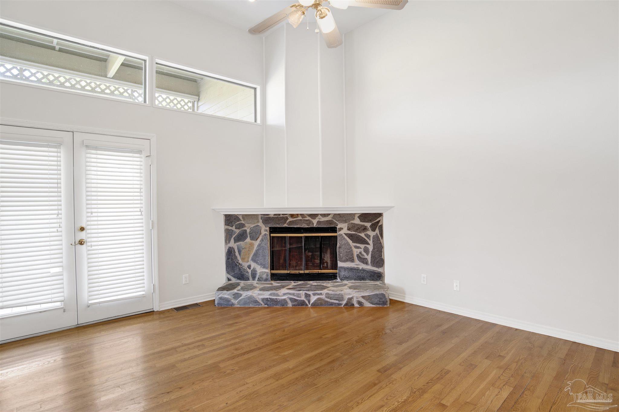 13414 Valerie Drive Pensacola, FL 32507 - Photo 12 of 35 an empty room with wooden floor fireplace and windows
