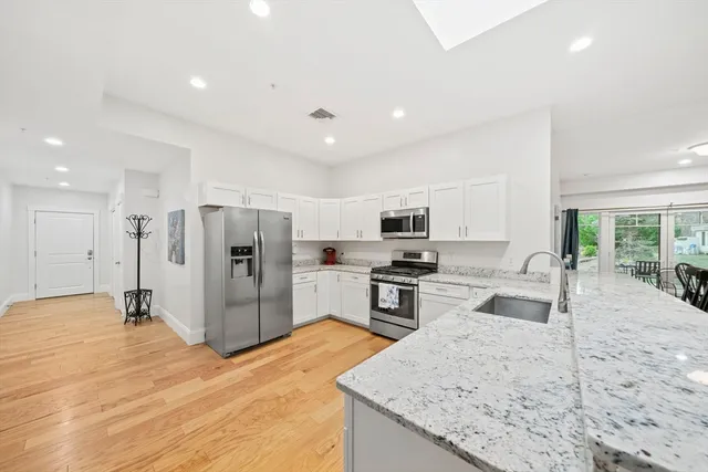 a large kitchen with stainless steel appliances granite countertop a refrigerator stove microwave and sink