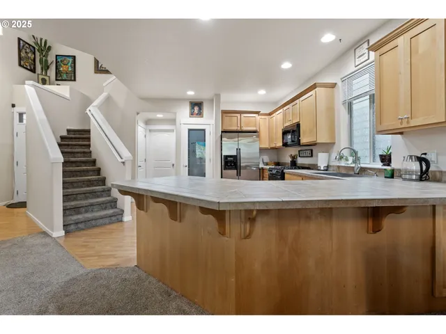 a kitchen with stainless steel appliances granite countertop a sink a stove and a refrigerator