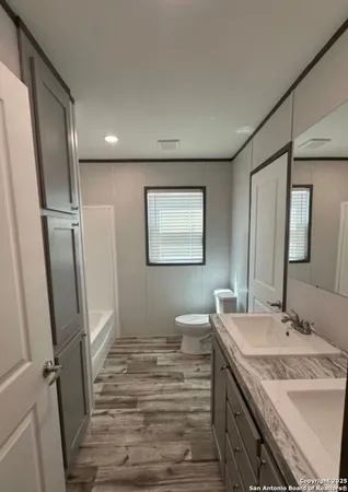 a bathroom with a sink a toilet a mirror and shower