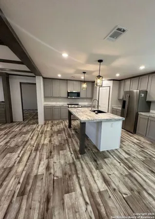 a large kitchen with stainless steel appliances a large counter top a stove and a refrigerator