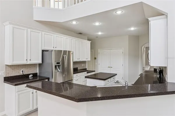 a kitchen with stainless steel appliances granite countertop a sink a refrigerator and a granite counter tops