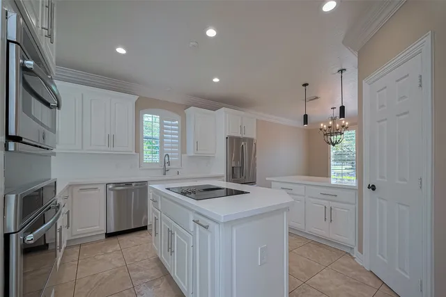 a kitchen that has a lot of white cabinets and stainless steel appliances