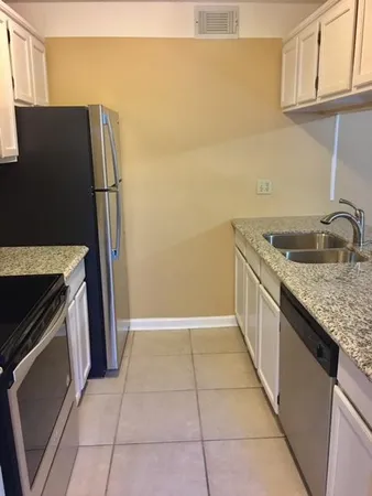 a kitchen with granite countertop a refrigerator and a sink