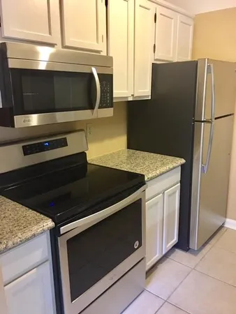 a kitchen with granite countertop white cabinets and stainless steel appliances