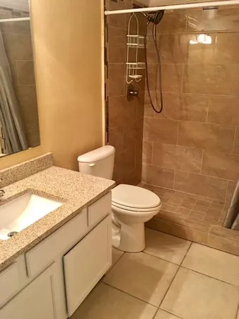 a bathroom with a granite countertop toilet a sink and shower