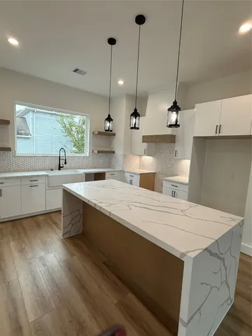 a kitchen with a stove a sink a window and wooden floor