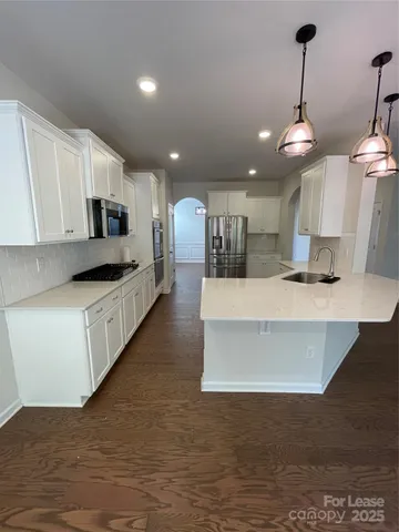 a kitchen with stainless steel appliances granite countertop a stove a sink and a microwave