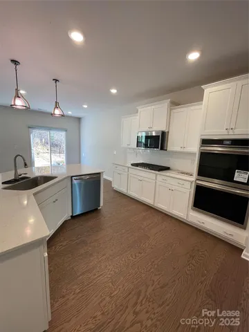 a room with stainless steel appliances wooden floor and a refrigerator