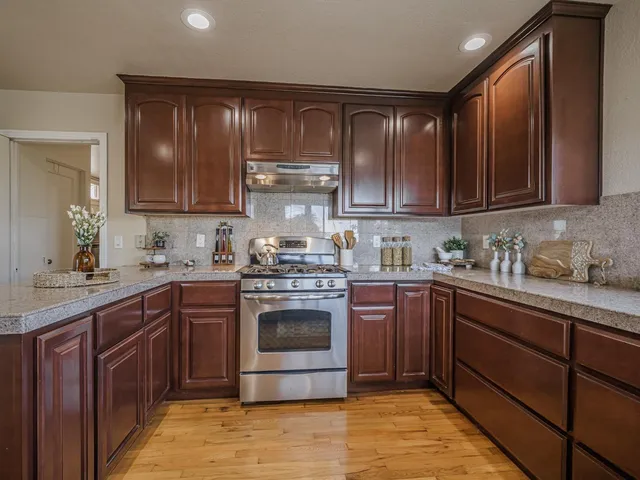 a kitchen with stainless steel appliances granite countertop wooden cabinets a stove top oven a sink and dishwasher