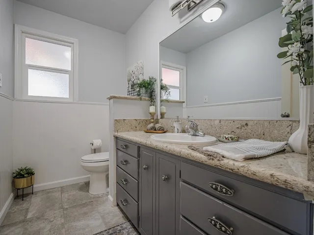 a bathroom with a granite countertop sink and a toilet