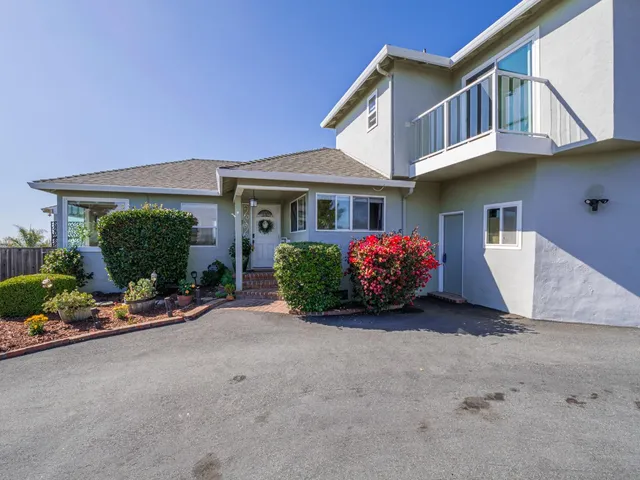 a view of a house with a yard and potted plants