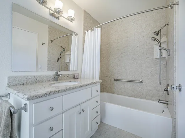 a bathroom with a granite countertop sink a mirror a shower and a bathtub