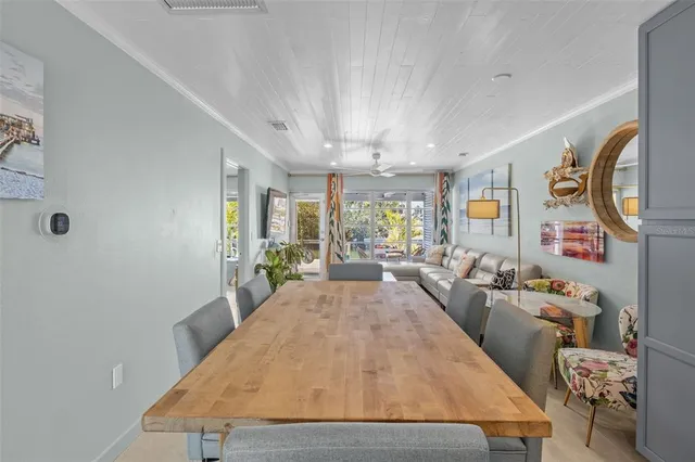 a kitchen with stainless steel appliances a dining table chairs refrigerator and cabinets