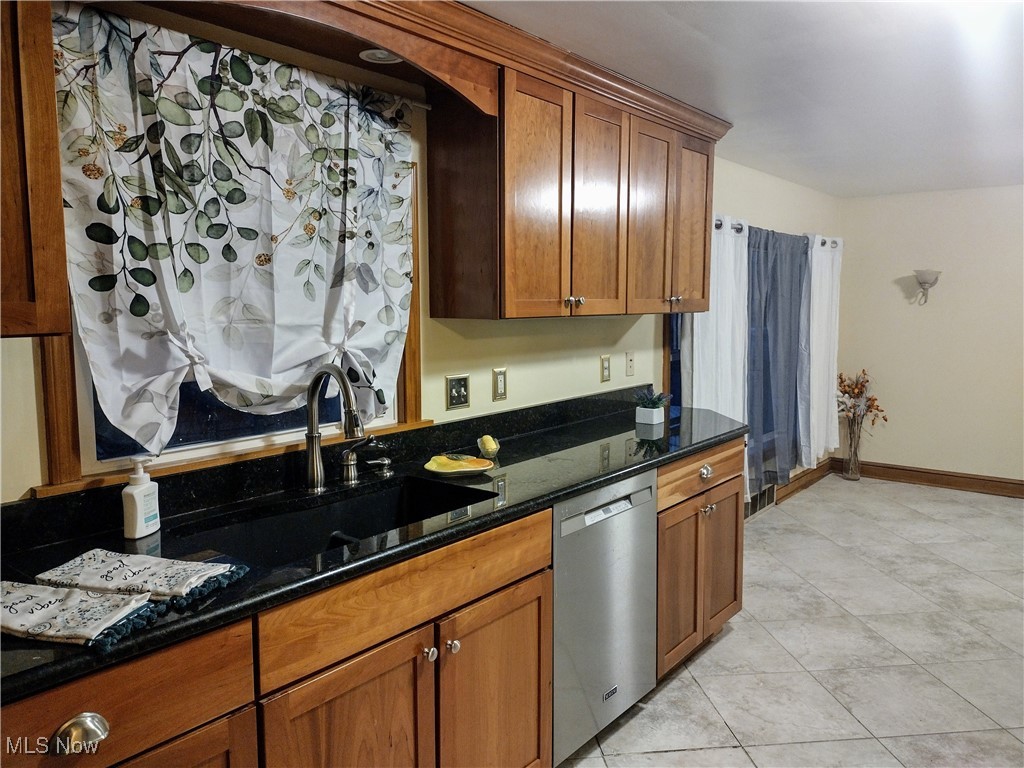 4376 22nd Street Northwest Canton, OH 44708 - Photo 5 of 10 Kitchen with dark stone countertops, baseboards, stainless steel dishwasher, a sink, and brown cabinets